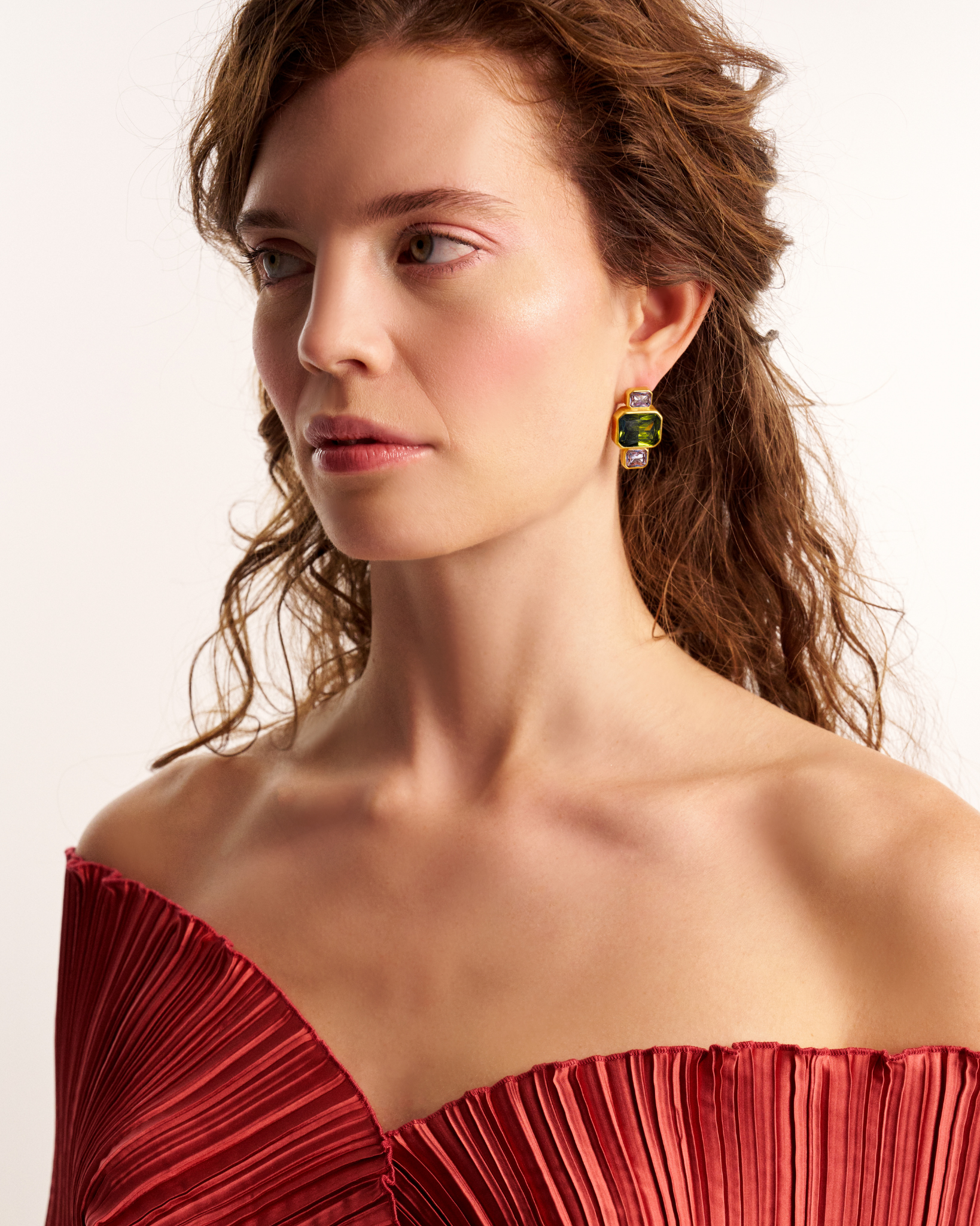 Woman wearing gold geometric gemstone earrings