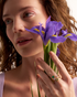 Woman wearing gold gemstone ring with purple iris flowers