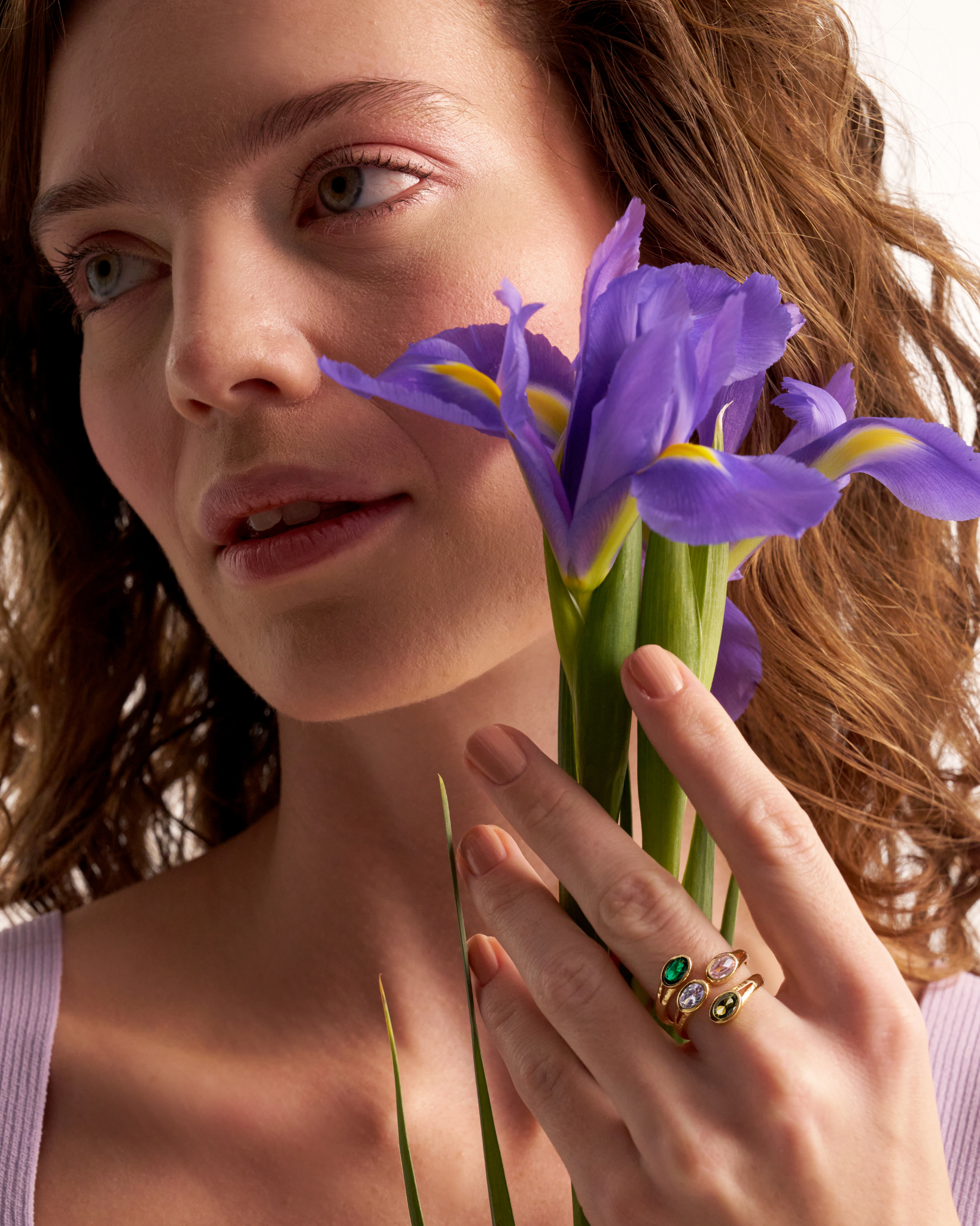 Woman wearing gold gemstone ring with purple iris flowers