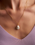 Woman wearing delicate pearl pendant necklace