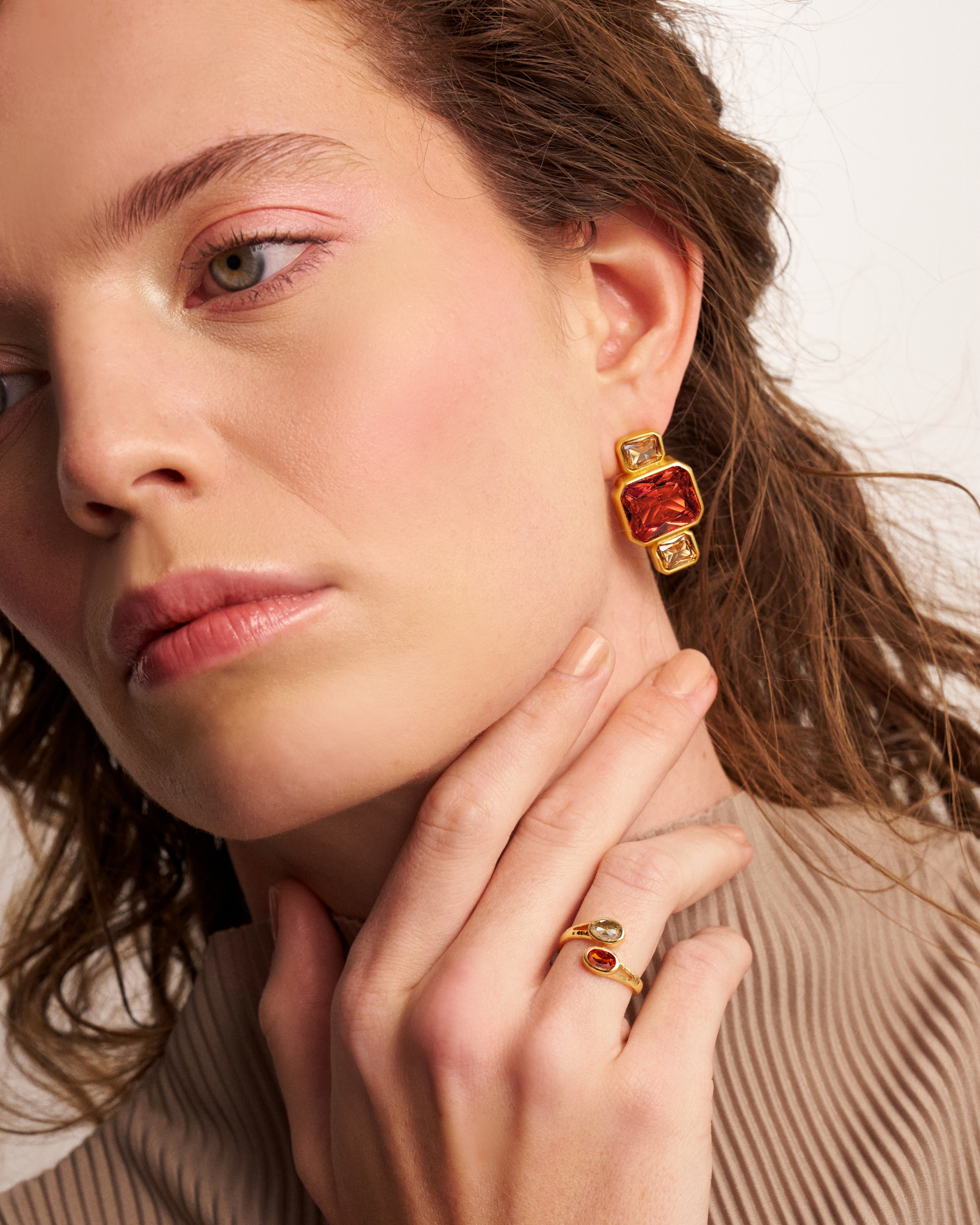 Woman wearing gold open ring with oval gemstones