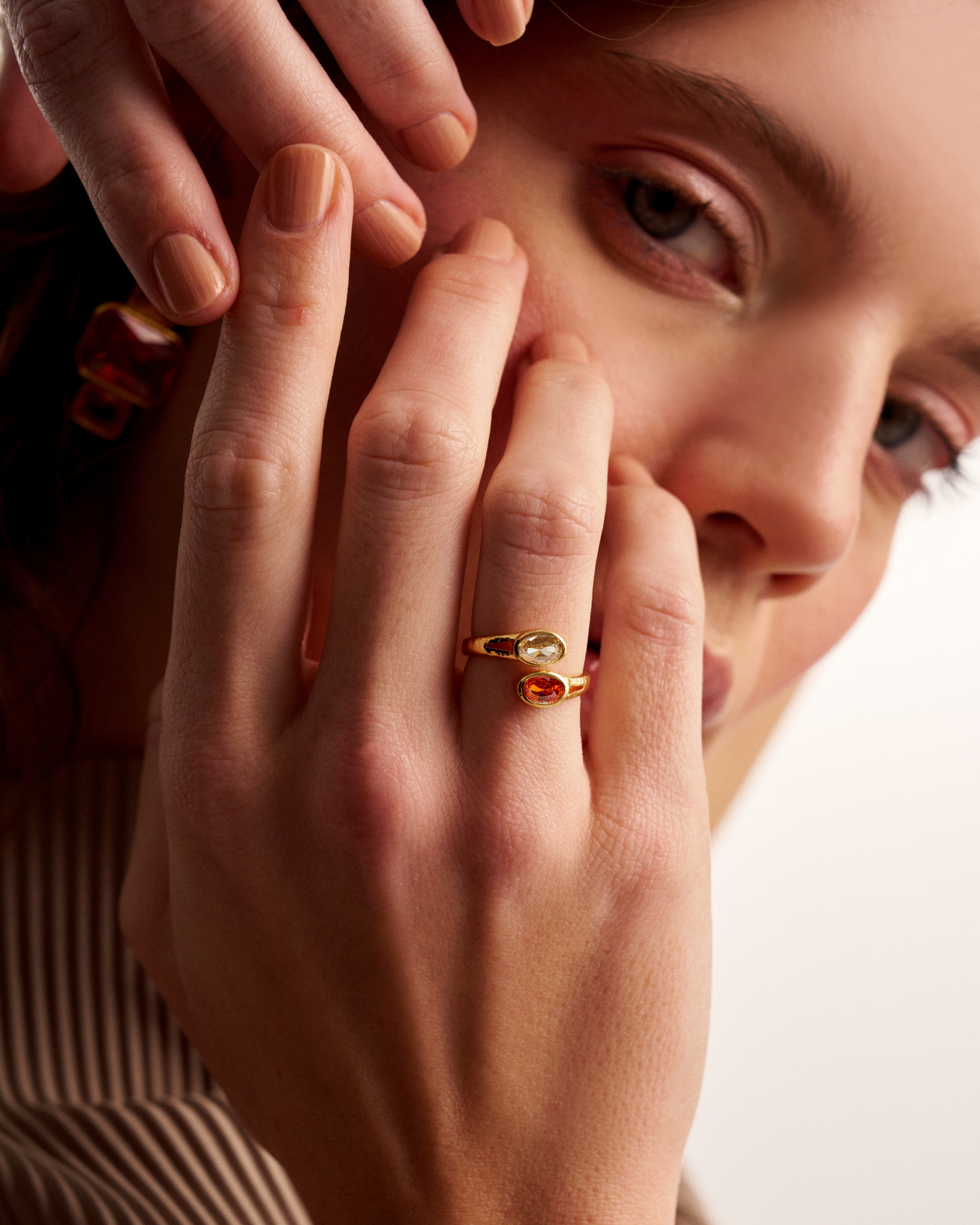 Woman wearing gold open ring with oval gemstones