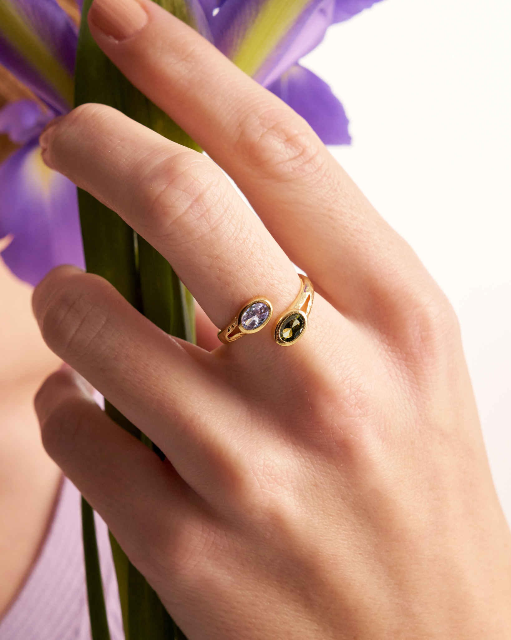 Woman wearing gold open ring with oval gemstones