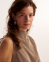 Woman wearing pink and green gemstone earrings