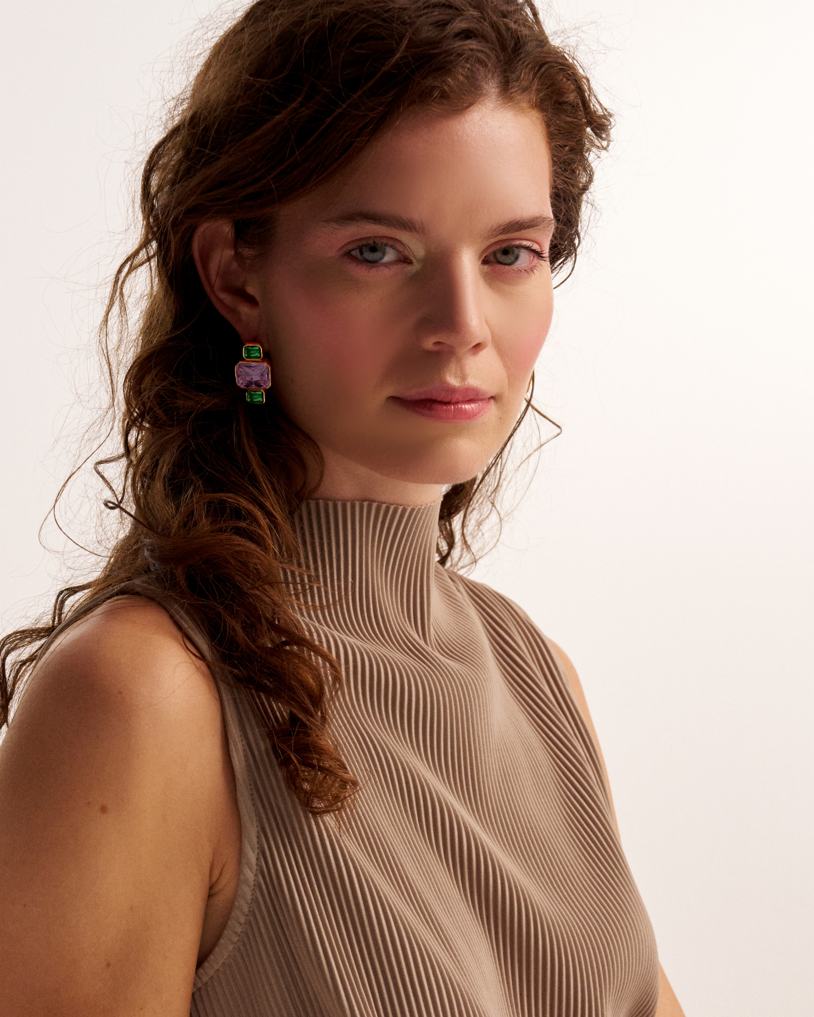 Woman wearing pink and green gemstone earrings