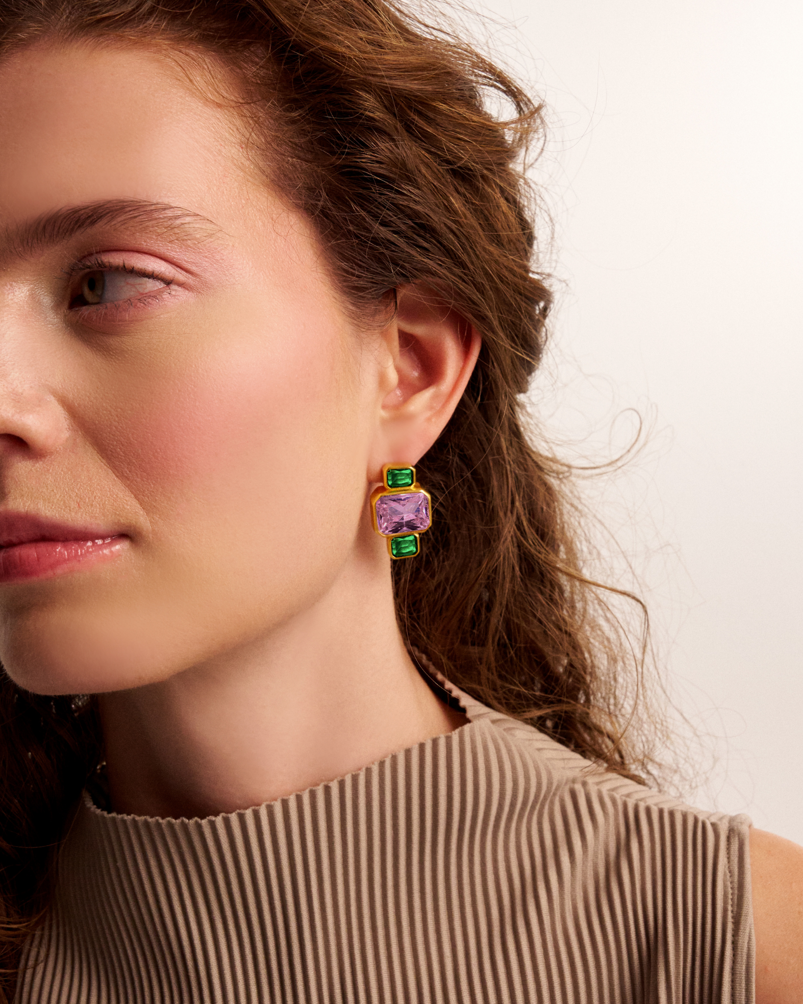 Woman wearing gold geometric gemstone earrings