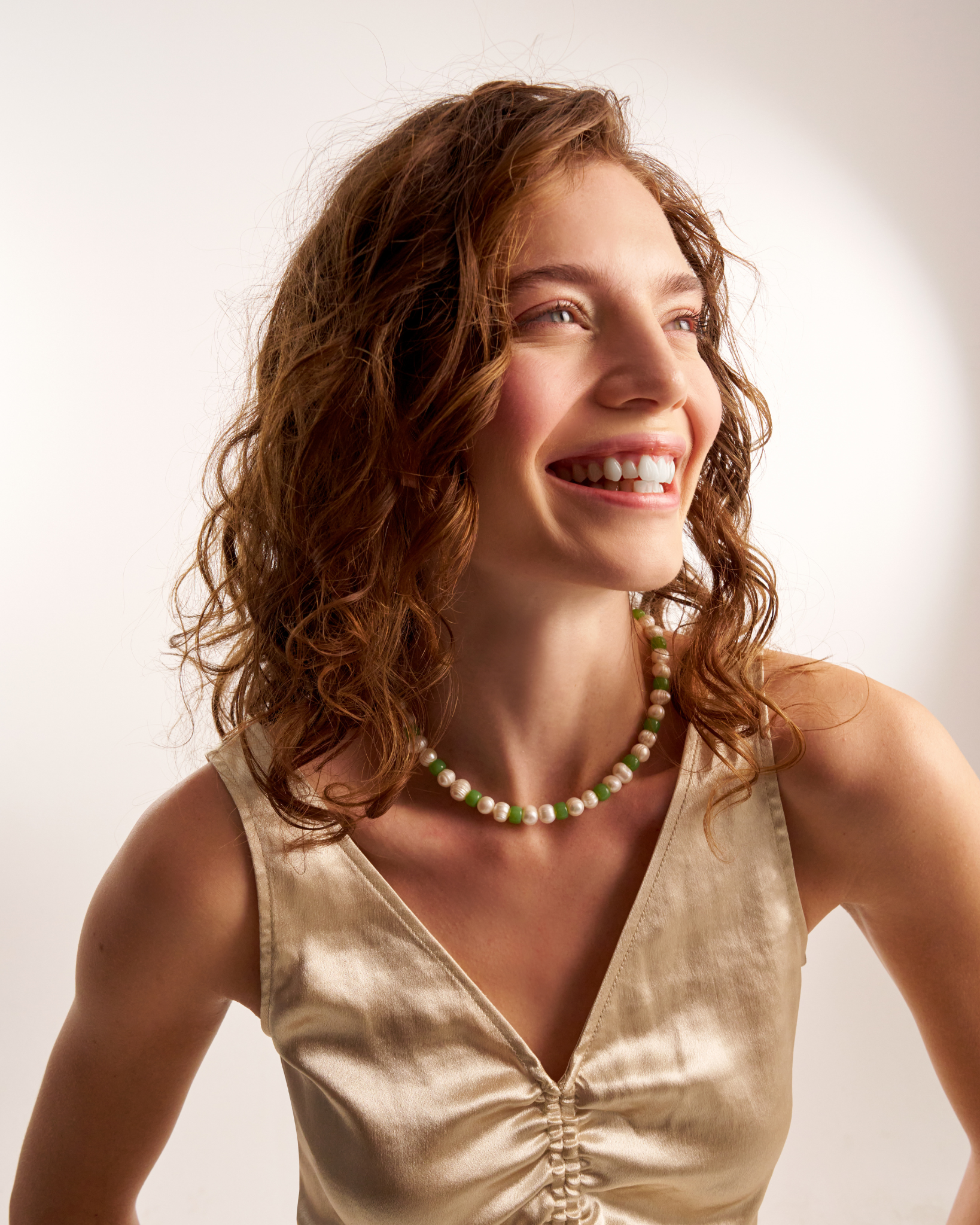 Smiling woman styling green beaded necklace
