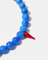 Close-up of blue agate beads and red glass chili charm