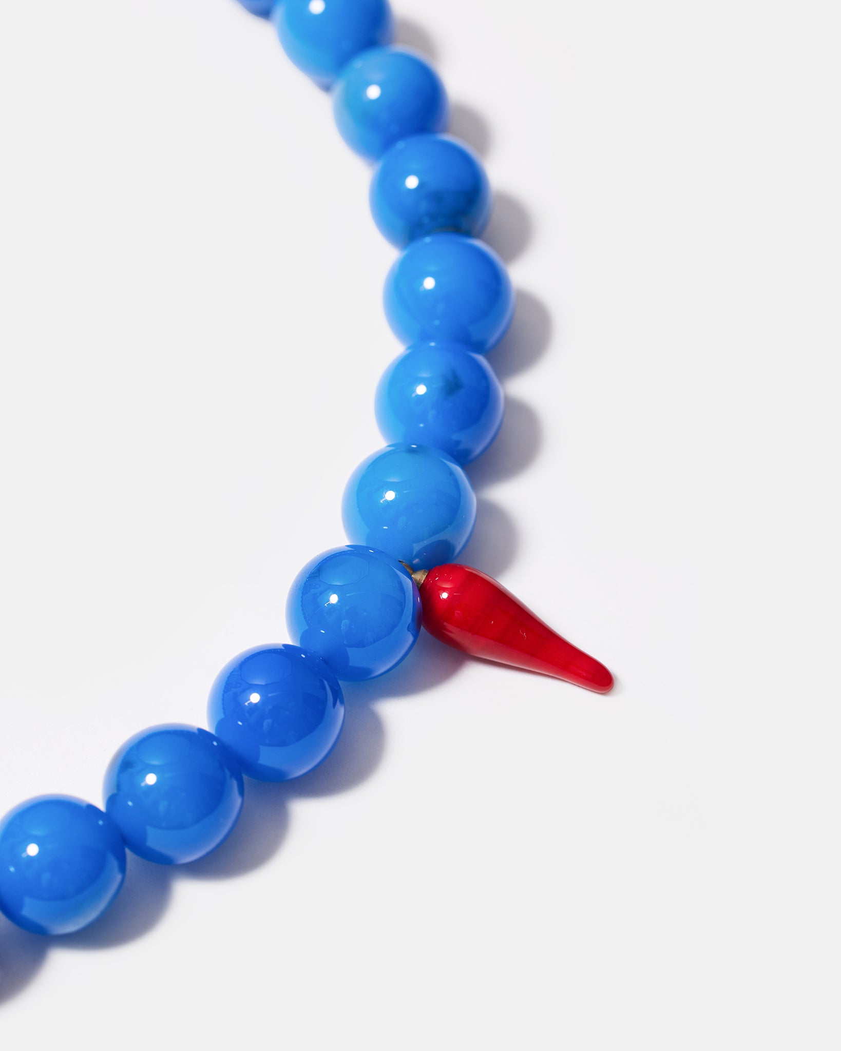 Close-up of blue agate beads and red glass chili charm