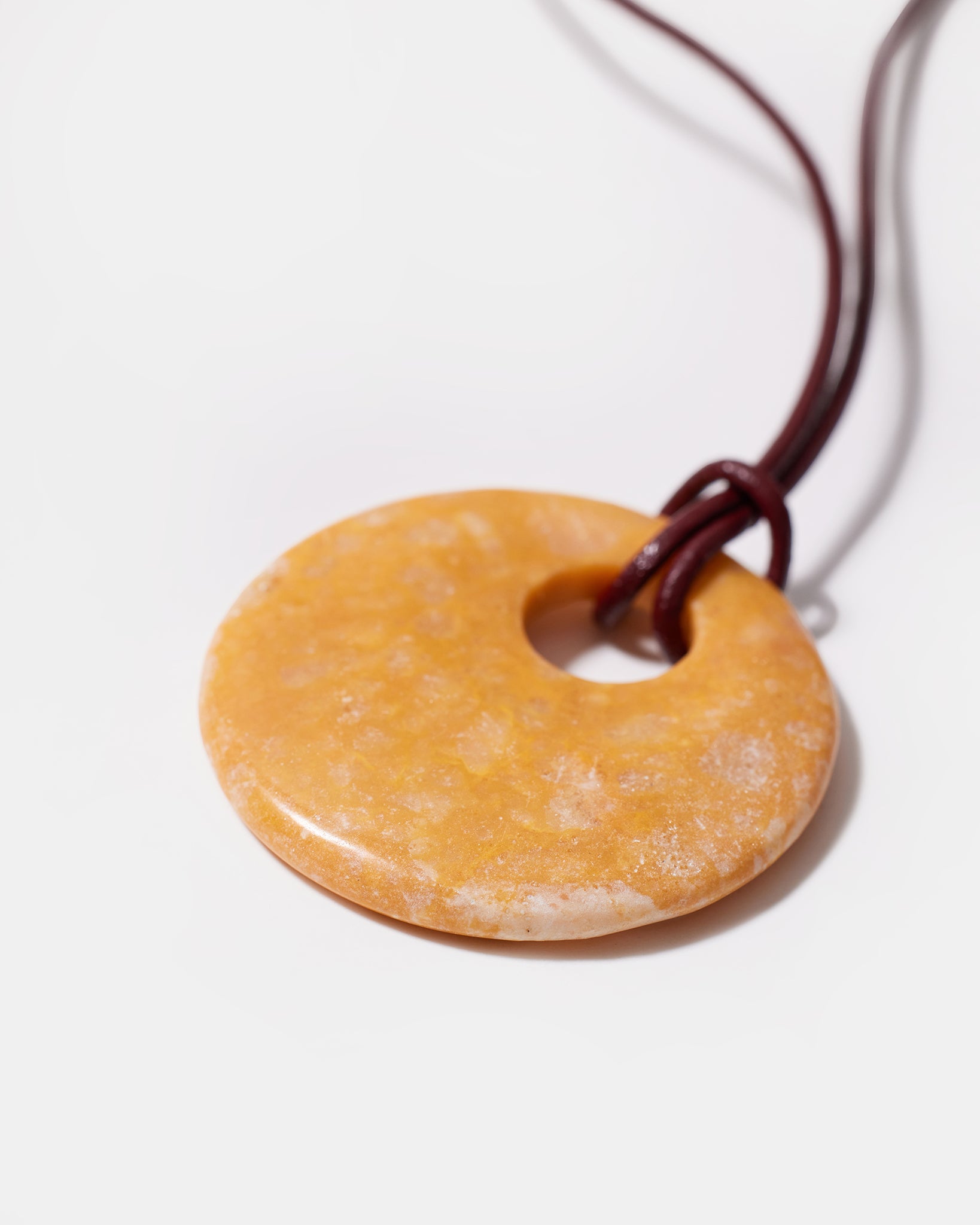Close-up of yellow calcite donut pendant with natural texture