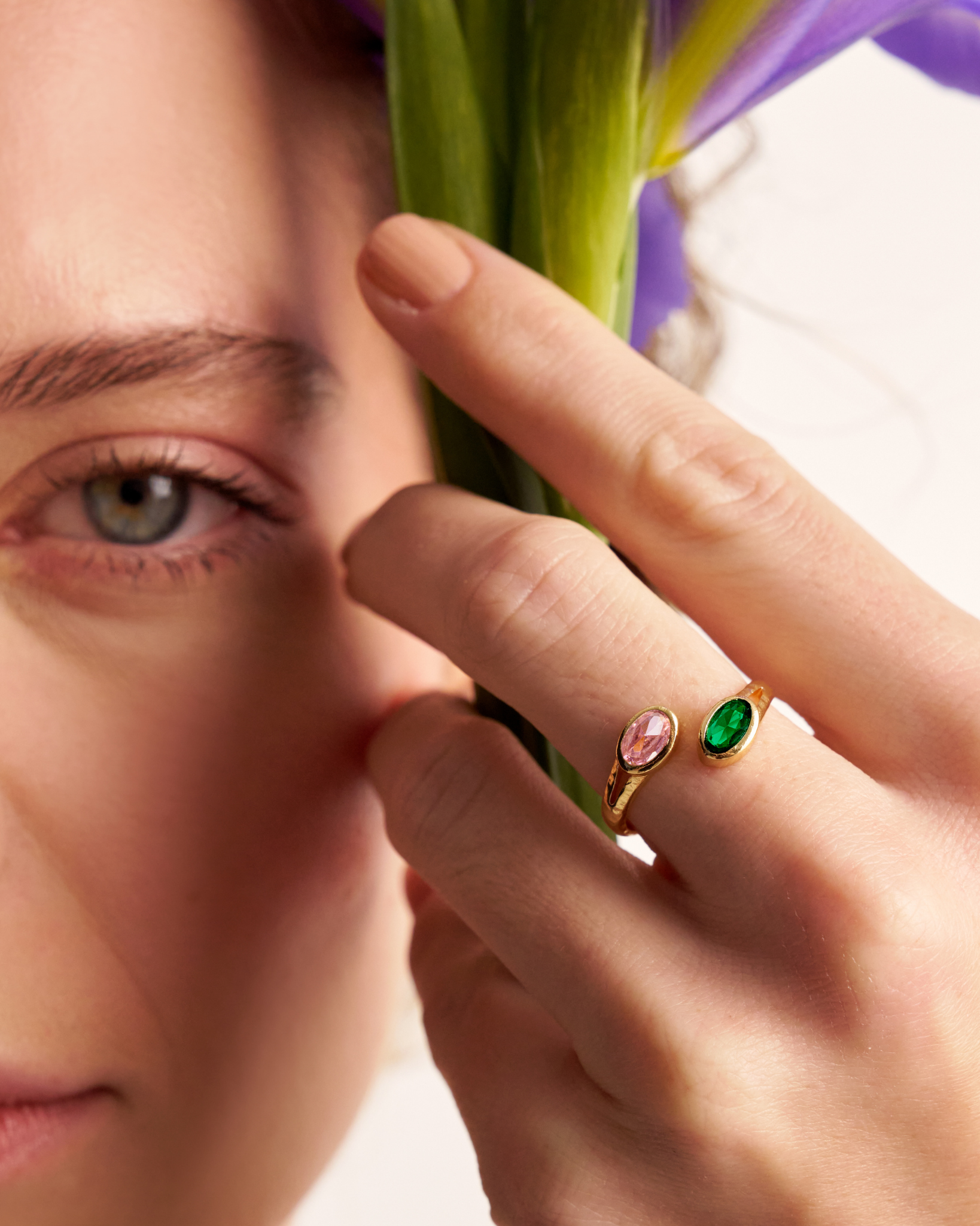 Woman wearing gold open ring with oval gemstones