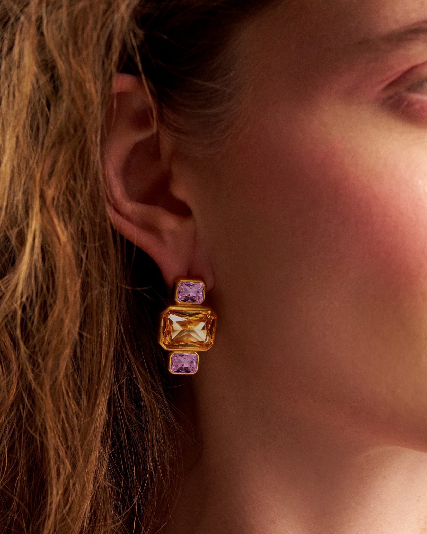 Close-up of woman wearing gold gemstone earrings
