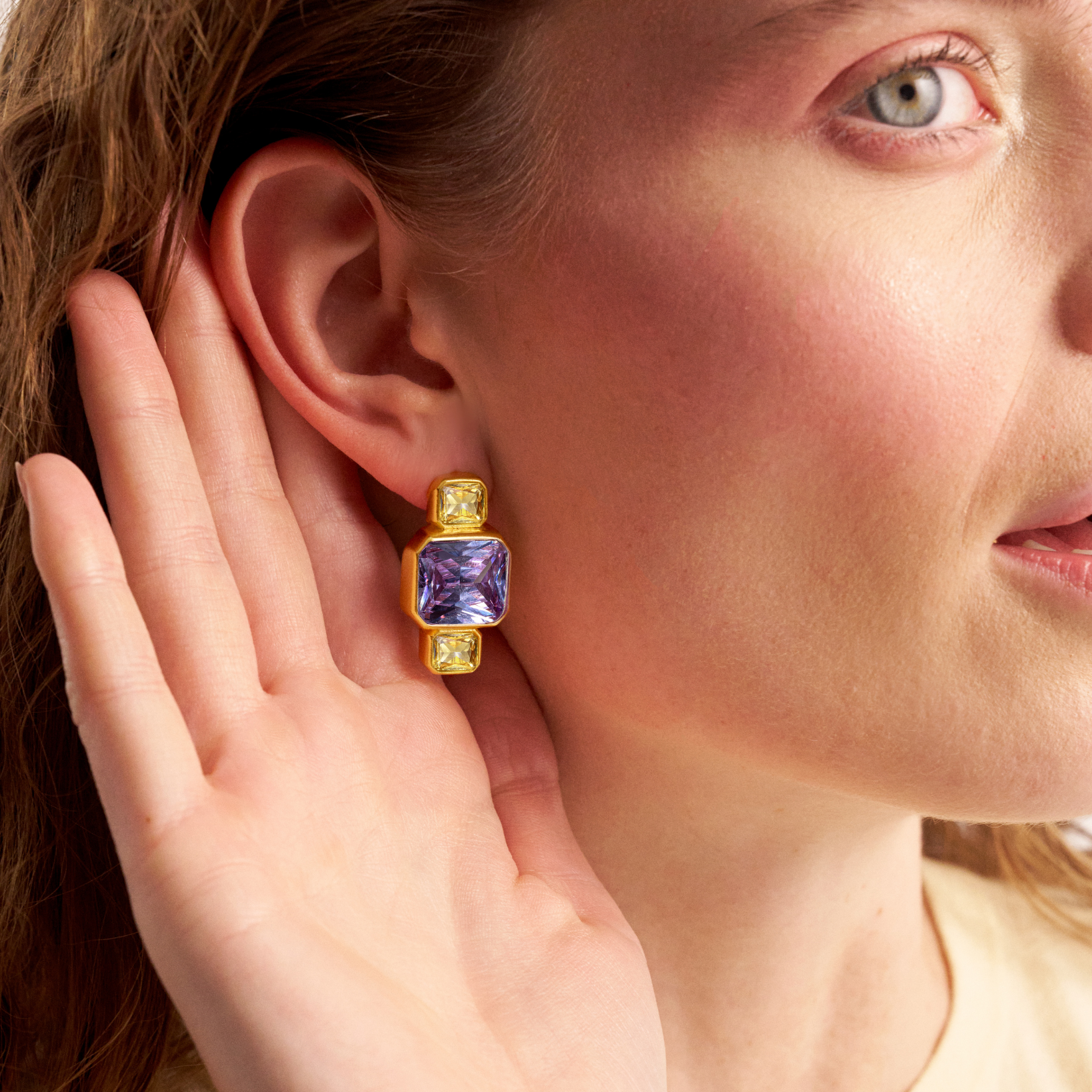Woman wearing gold geometric gemstone earrings