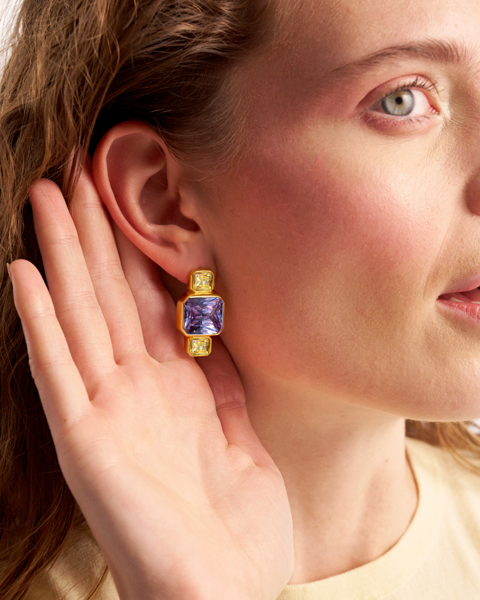 Woman wearing gold geometric gemstone earrings