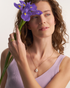 Woman wearing gold dome cocktail ring with purple iris flower
