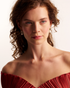 Woman wearing gold pearl statement earrings
