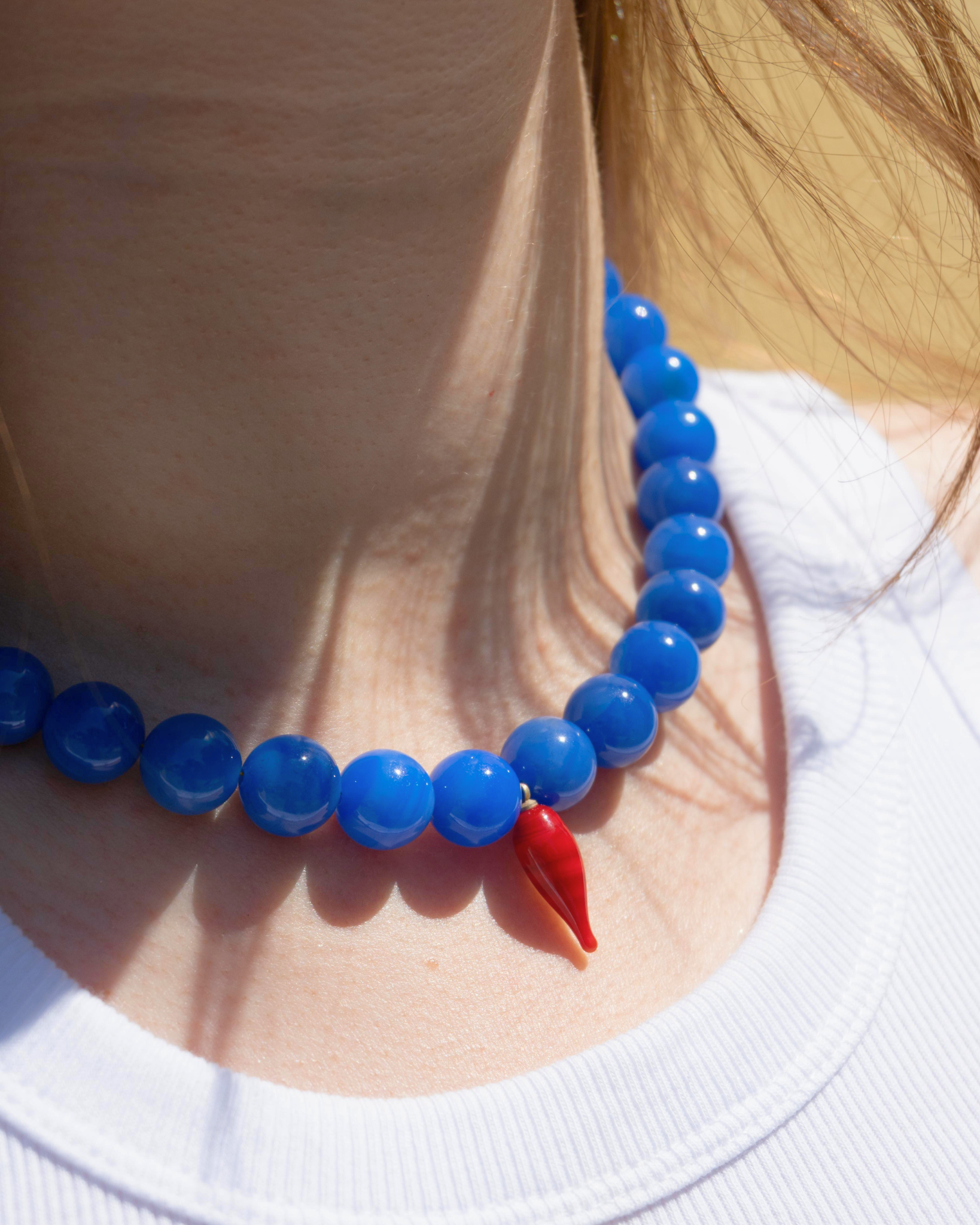 Woman wearing blue agate necklace with red chili pepper pendant