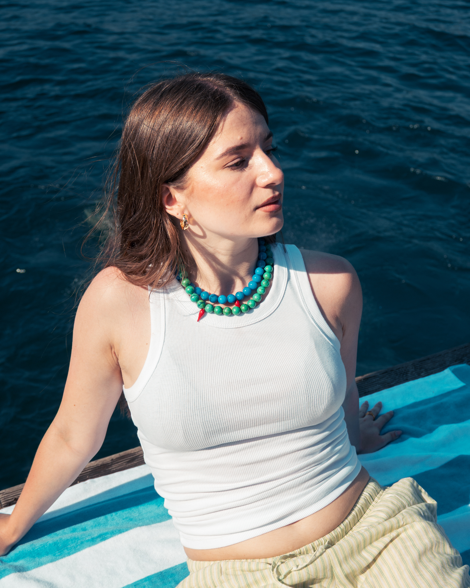 Woman wearing turquoise statement necklace by the sea