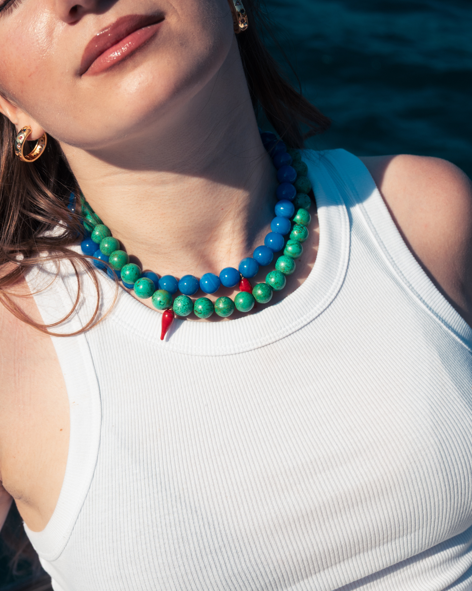 Woman wearing turquoise gemstone necklace with red chili pepper charm